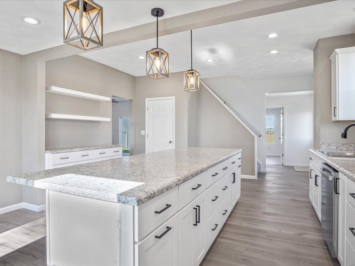 Kitchen with dishwasher, a kitchen island, white cabinetry, and hanging light fixtures