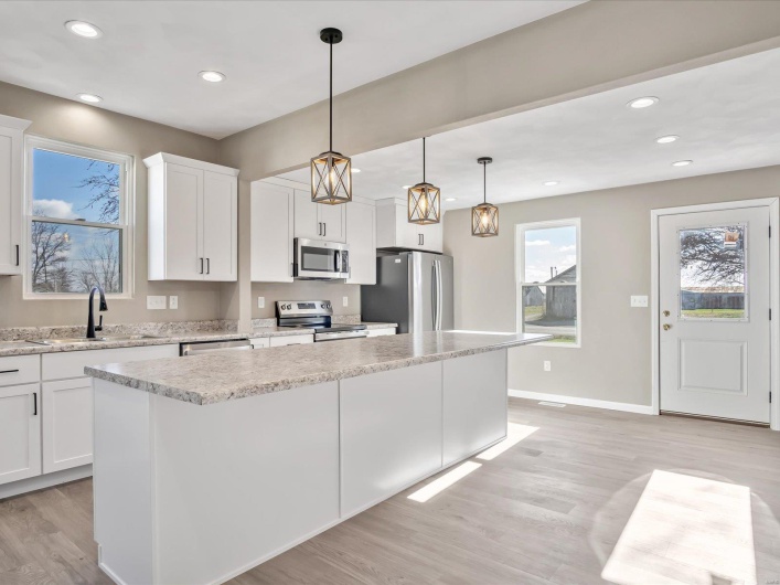 Kitchen featuring white cabinets, appliances with stainless steel finishes, a kitchen island, and sink