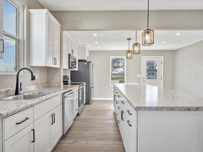 Kitchen with a center island, sink, decorative light fixtures, white cabinetry, and stainless steel appliances