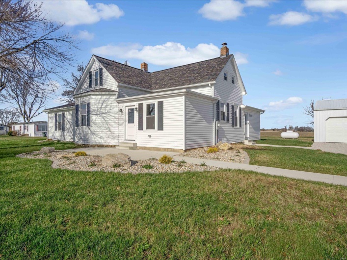 View of side of home featuring an outbuilding, a garage, and a lawn