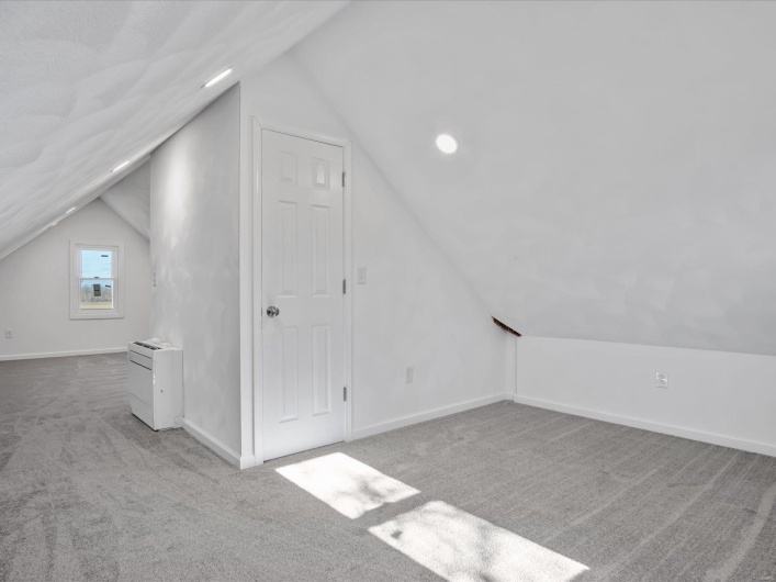 Additional living space with light carpet and lofted ceiling