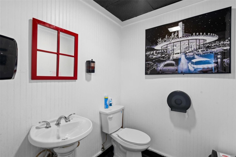 Bathroom with wood walls, sink, crown molding, and toilet