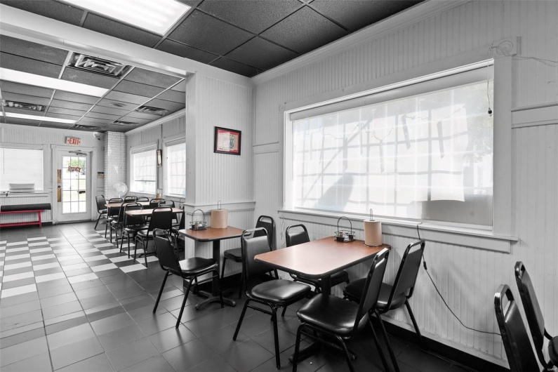 Dining area with tile patterned floors, a paneled ceiling, and crown molding