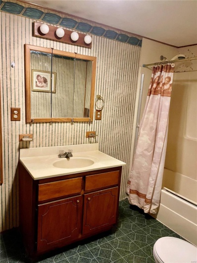 Full bathroom with vanity, toilet, crown molding, and shower / tub combo with curtain