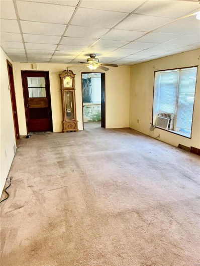 Unfurnished living room with light colored carpet, a drop ceiling, cooling unit, and ceiling fan