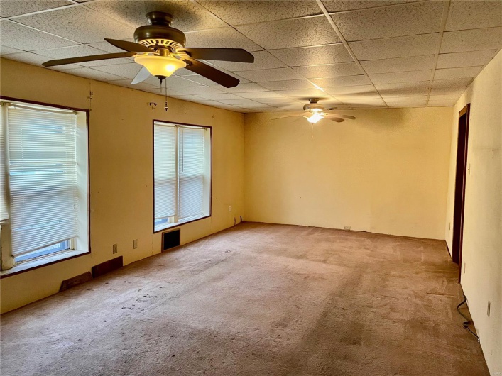Carpeted empty room with a drop ceiling and ceiling fan