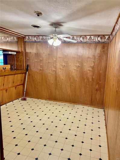Unfurnished dining area with a textured ceiling, ceiling fan, and wood walls