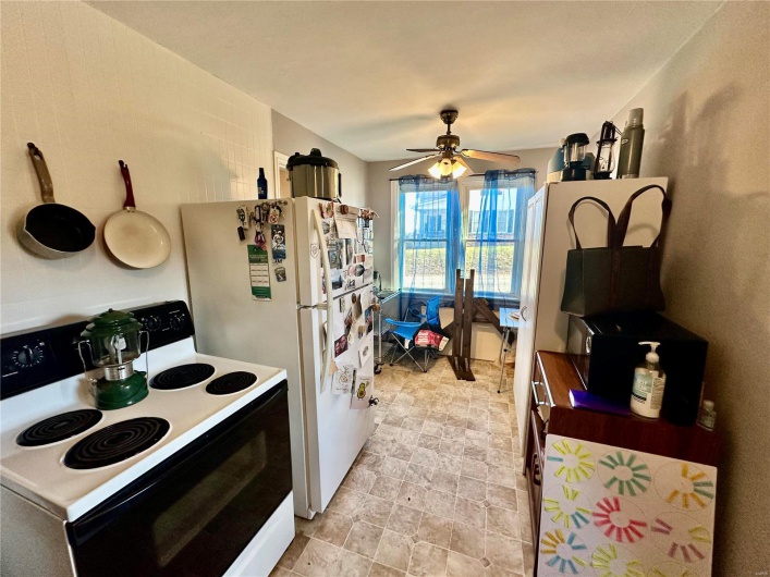 Kitchen with ceiling fan, white fridge, and electric stove