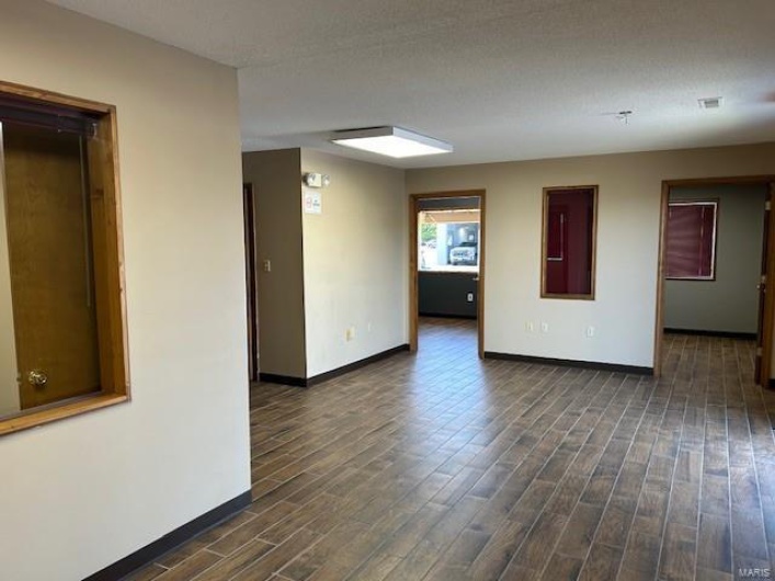 Spare room with dark wood-type flooring and a textured ceiling
