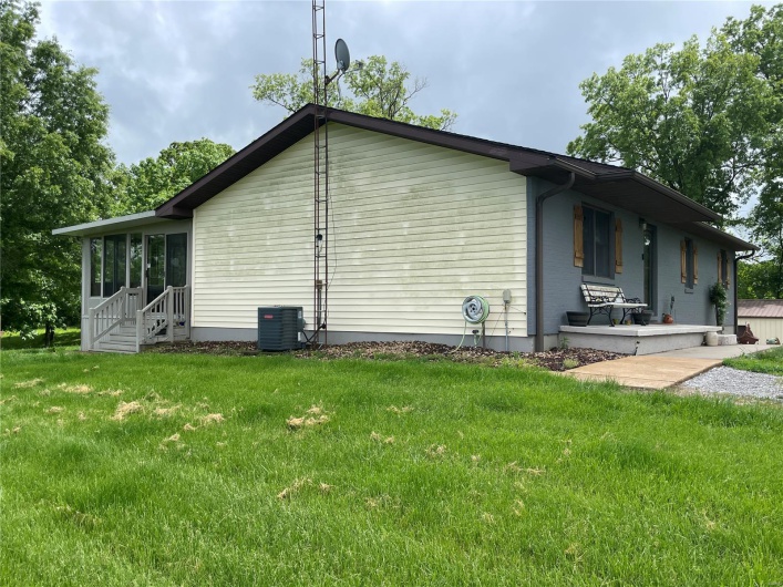 View of property exterior with a lawn and cooling unit