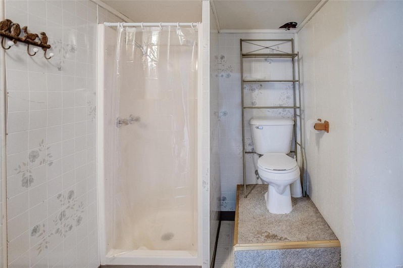 Bathroom with tile walls, toilet, and a shower with curtain