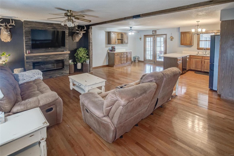 Living room with a large fireplace, a textured ceiling, french doors, light hardwood / wood-style floors, and sink