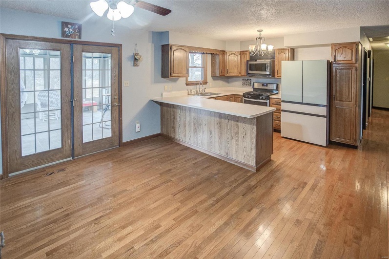 Kitchen featuring kitchen peninsula, decorative light fixtures, stainless steel appliances, french doors, and light hardwood / wood-style floors