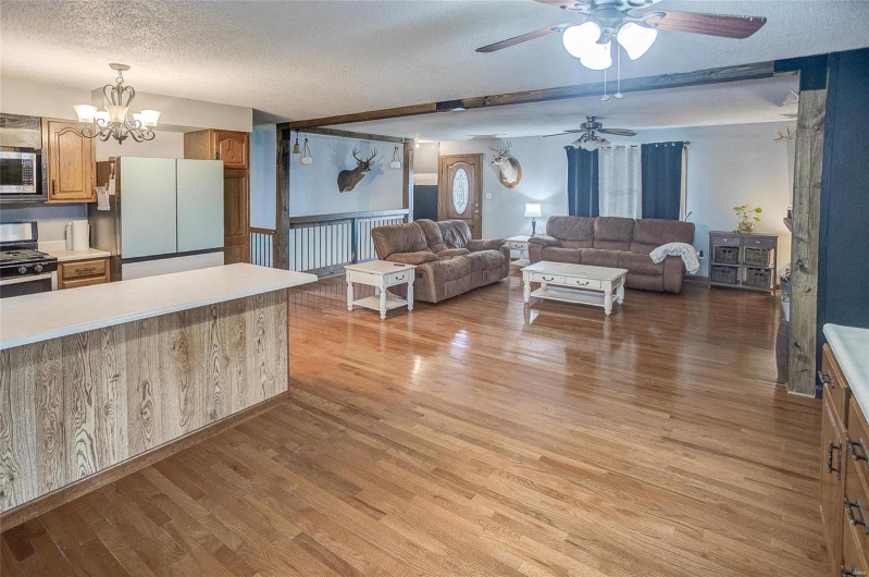Kitchen featuring fridge, a textured ceiling, gas range oven, beamed ceiling, and light wood-type flooring