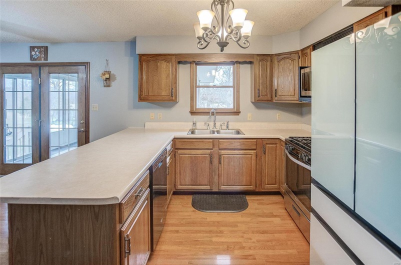 Kitchen with a textured ceiling, decorative light fixtures, a notable chandelier, appliances with stainless steel finishes, and sink
