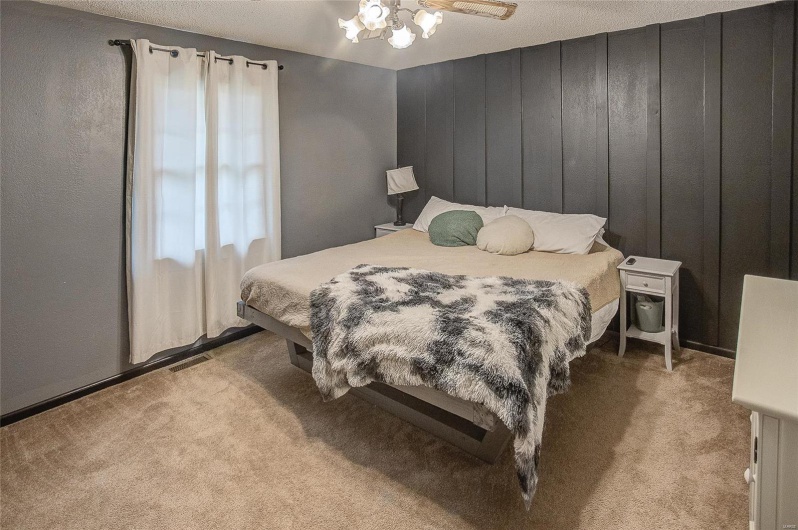 Carpeted bedroom featuring ceiling fan with notable chandelier and a textured ceiling