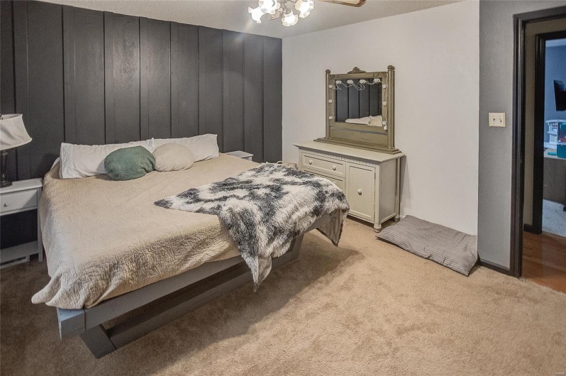 Bedroom featuring an inviting chandelier, wood walls, and light carpet