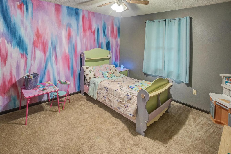 Carpeted bedroom with a textured ceiling and ceiling fan