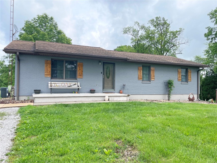 View of front of house with brick siding, a front lawn, central AC, a porch, and roof with shingles