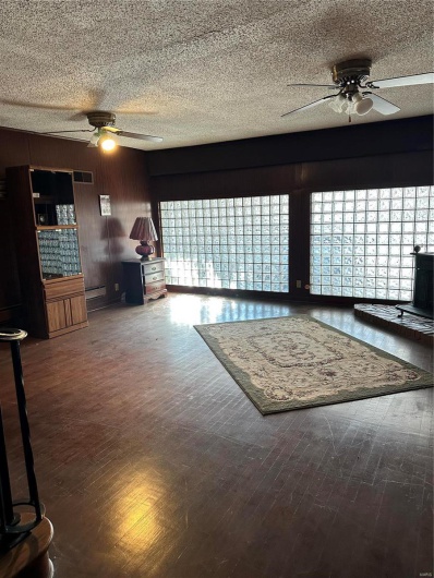 Unfurnished living room featuring ceiling fan, wood-type flooring, and a textured ceiling