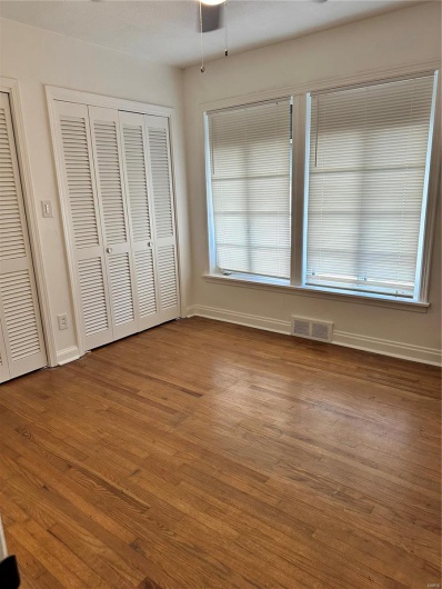 Unfurnished bedroom with two closets and wood-type flooring