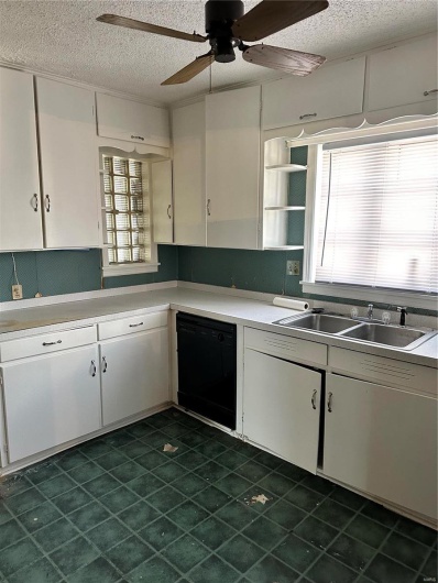 Kitchen with sink, dishwashing machine, white cabinets, and a textured ceiling