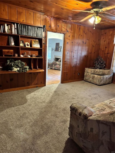 Sitting room with carpet, ceiling fan, wood walls, and wooden ceiling
