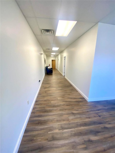 Corridor with a drop ceiling and dark hardwood / wood-style floors