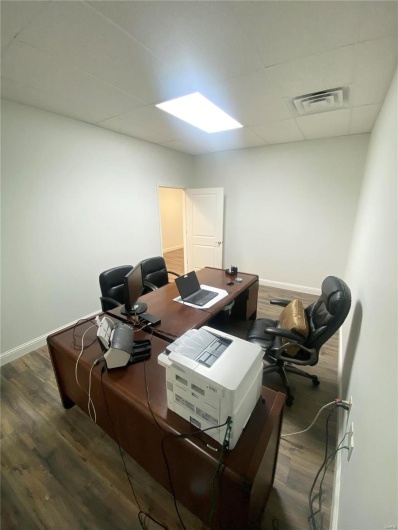 Home office featuring dark wood-type flooring and a paneled ceiling