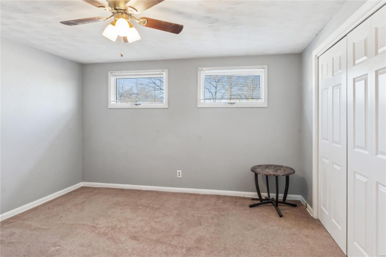 Carpeted bedroom with ceiling fan and large closet