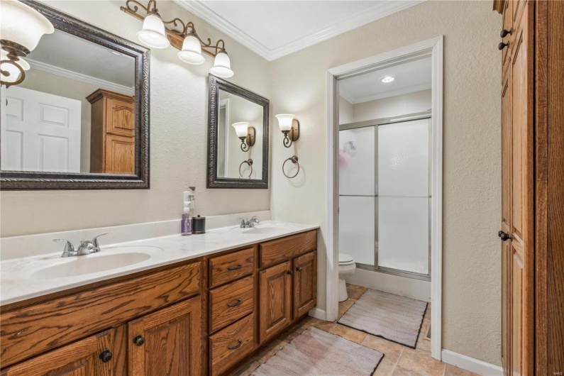 Bathroom with crown molding, shower, and a double vanity.