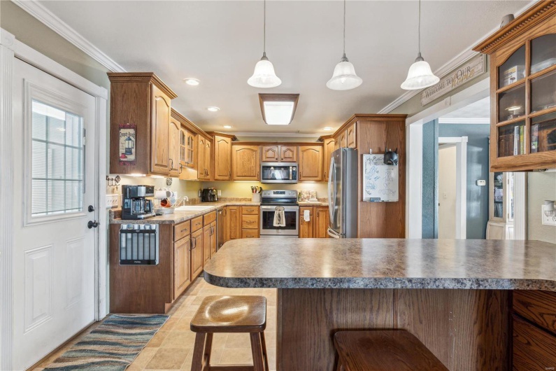 Kitchen featuring a breakfast bar, appliances with stainless steel finishes, crown molding, and decorative light fixtures