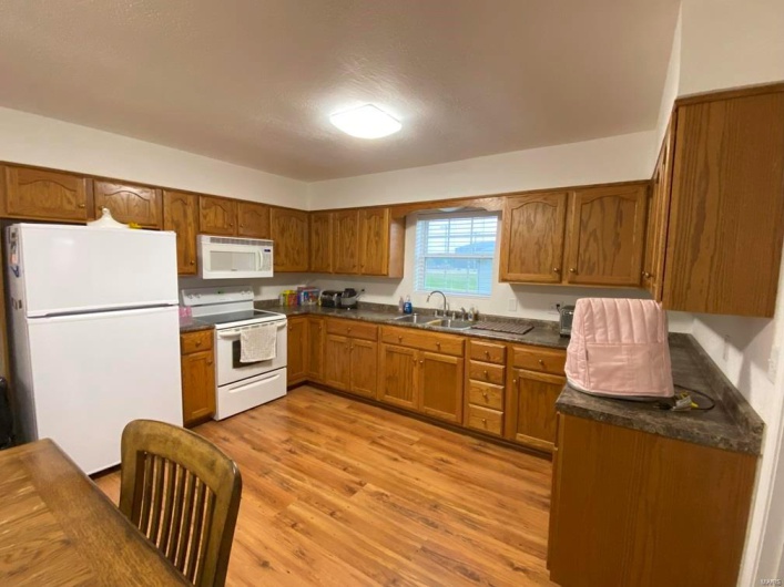 Kitchen featuring sink, white appliances, and light wood-type flooring