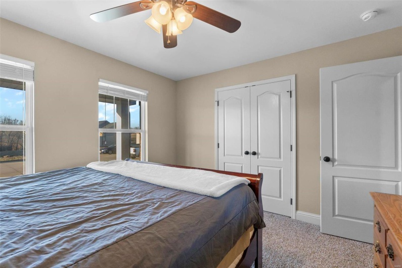 Bedroom featuring light colored carpet, ceiling fan, a closet, and multiple windows