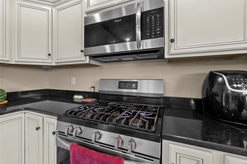 Kitchen featuring white cabinetry, stainless steel appliances, and dark stone counters