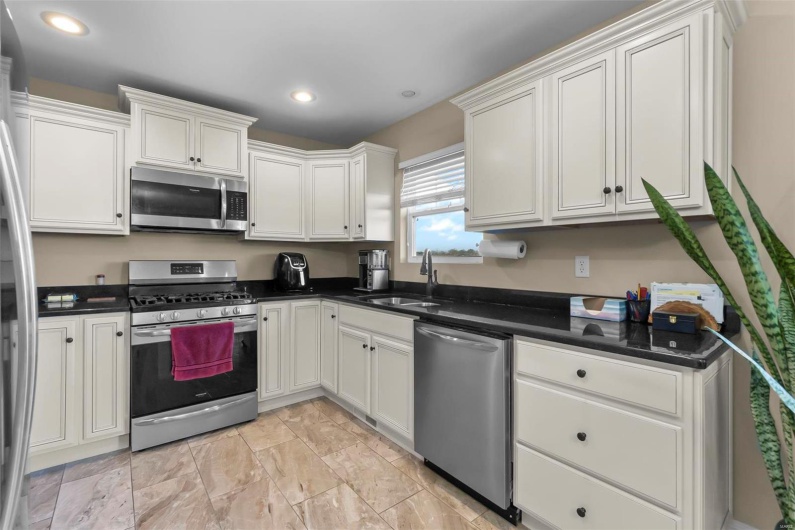 Kitchen with white cabinetry, stainless steel appliances, and sink