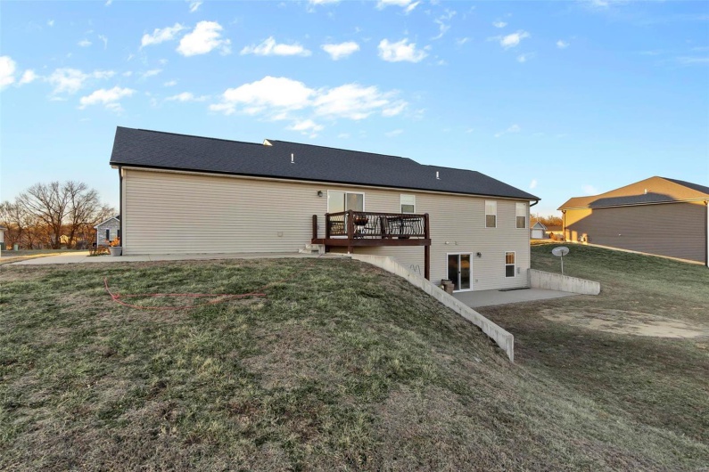 Rear view of property featuring a wooden deck, a yard, and a patio