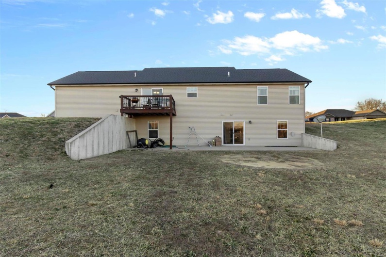 Back of property with a yard, a deck, and a patio