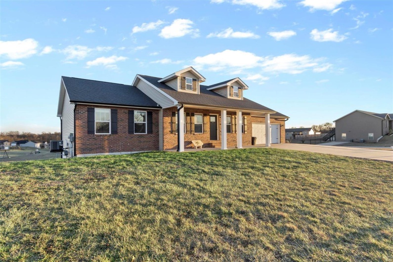View of front of home featuring a porch, a garage, and a front lawn