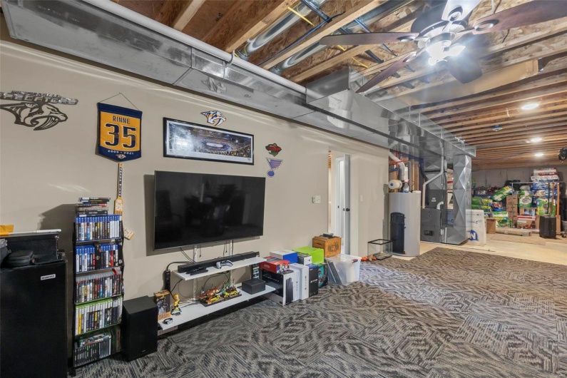 Basement with ceiling fan, carpet flooring, heating unit, and gas water heater