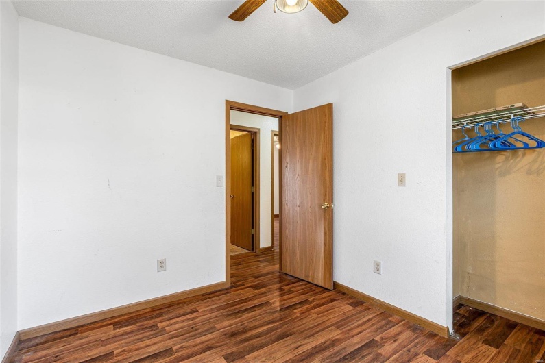 Unfurnished bedroom featuring dark hardwood / wood-style flooring, ceiling fan, and a closet