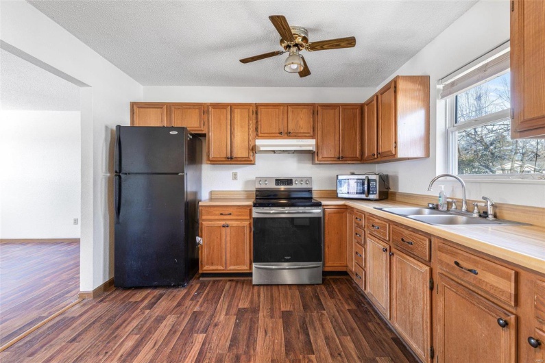 Kitchen with sink, a textured ceiling, dark hardwood / wood-style floors, ceiling fan, and stainless steel appliances