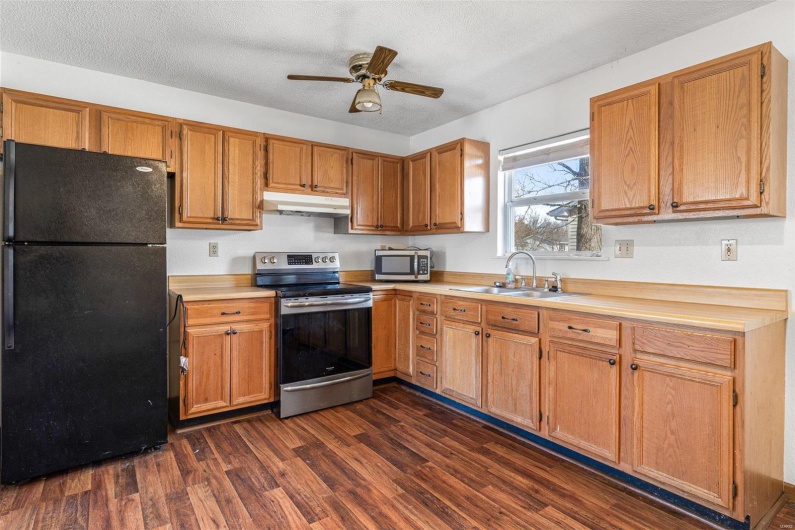 Kitchen with sink, a textured ceiling, appliances with stainless steel finishes, dark hardwood / wood-style flooring, and ceiling fan