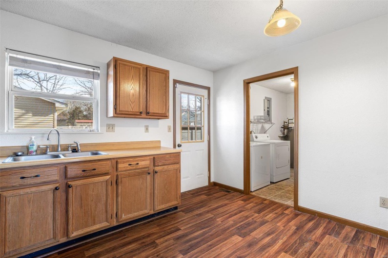 Kitchen featuring sink, dark wood-type flooring, hanging light fixtures, independent washer and dryer, and a textured ceiling