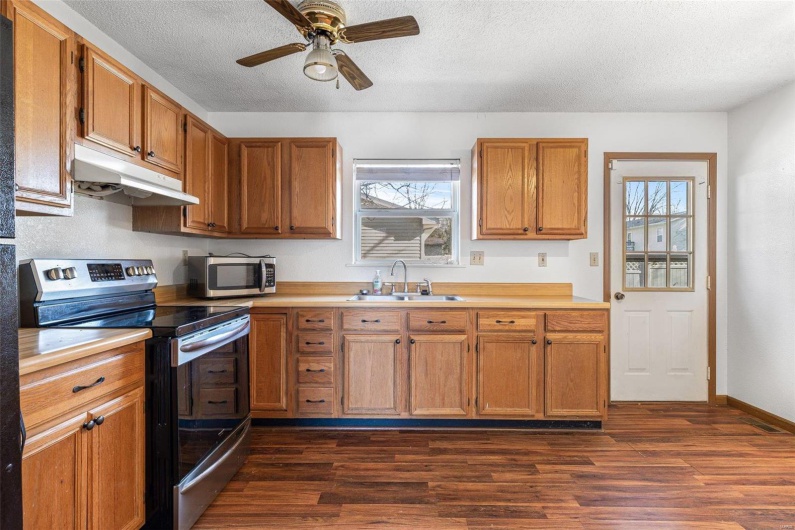 Kitchen with appliances with stainless steel finishes, sink, dark wood-type flooring, and a textured ceiling