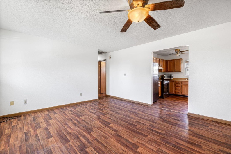 Unfurnished living room with dark wood-type flooring and a textured ceiling
