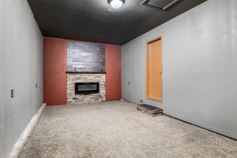 Unfurnished living room with a stone fireplace and carpet flooring