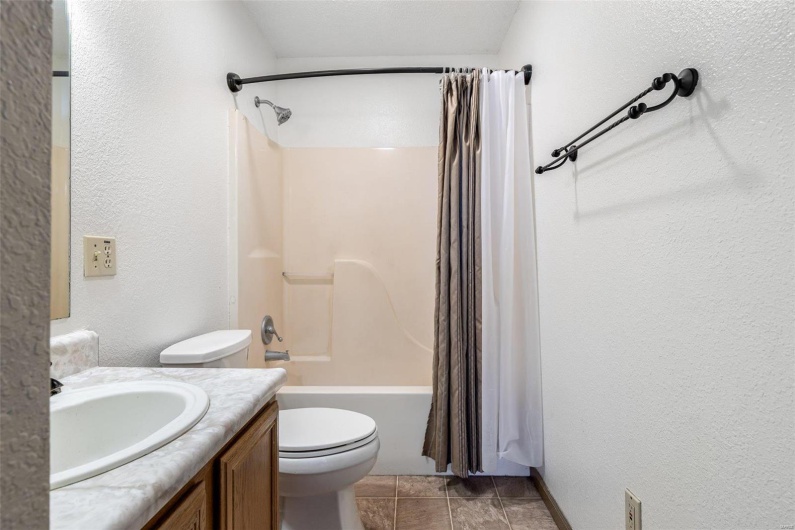 Full bathroom with vanity, shower / tub combo with curtain, and toilet