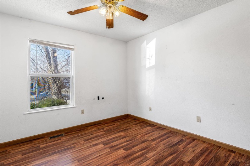 Spare room with a healthy amount of sunlight, dark wood-type flooring, a textured ceiling, and ceiling fan
