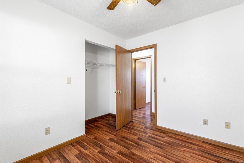 Unfurnished bedroom featuring dark hardwood / wood-style flooring, a textured ceiling, ceiling fan, and a closet